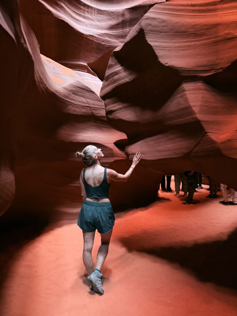 Woman standing in upper Antelope Canyon looking up at the formations. 