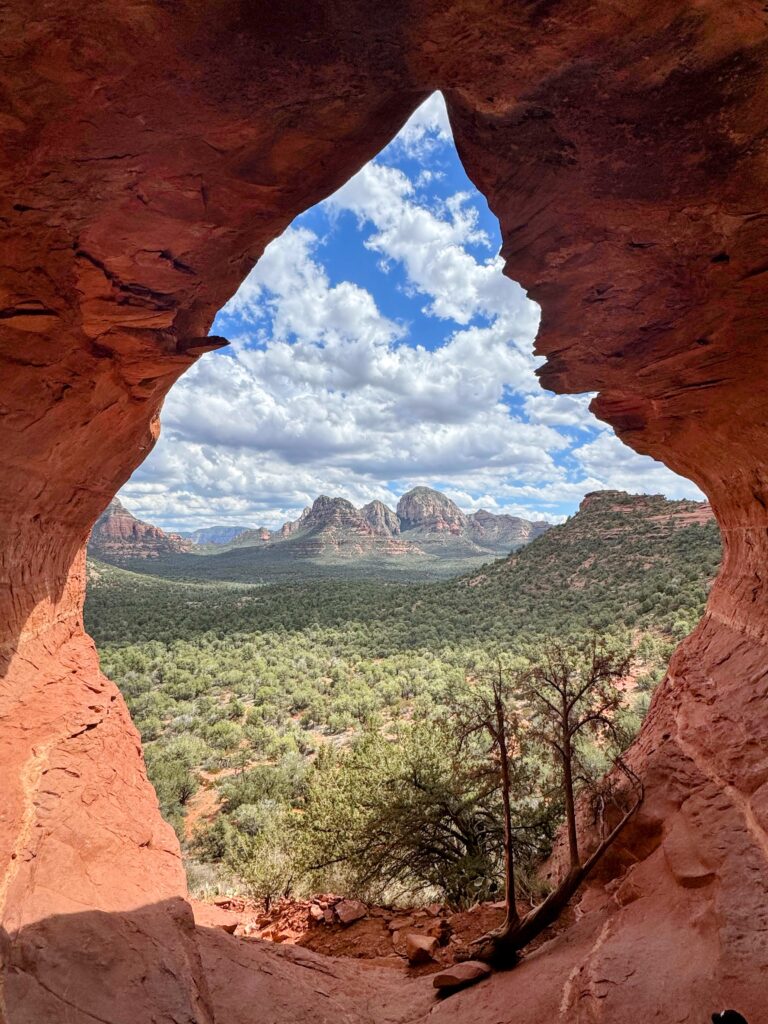 The inside of a cave looking out onto red mountains in Sedona, Arizona. 
