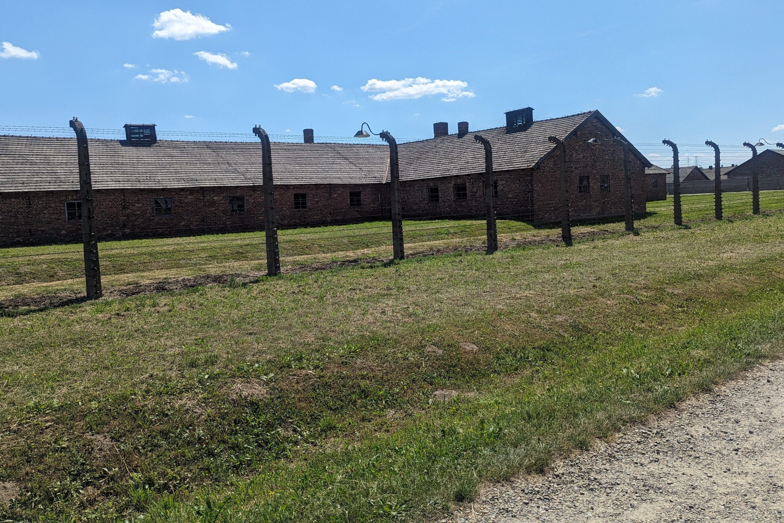 Exterior of housing in Auschwitz II-Birkenau behind a barb wired fence.