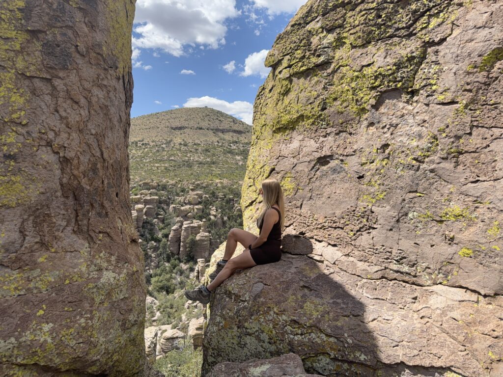 Woman sitting on a rock high above hoodoos, looking out.
